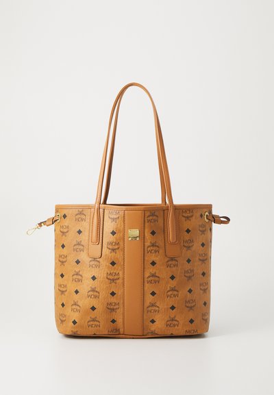 Borsa tote in pelle marrone chiaro con manici doppi, loghi MCM neri, motivi a diamante e una piccola targhetta dorata con il marchio al centro anteriore.