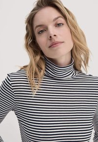 Turtleneck-Oberteil mit navy- und weißen Streifen. Der Stoff ist glatt mit einer weichen Textur und schmiegt sich eng an den Körper.