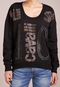 Sudadera negra con un amplio escote circulares y mangas largas, adornada con brillantes rhinestones que forman diseños de texto.