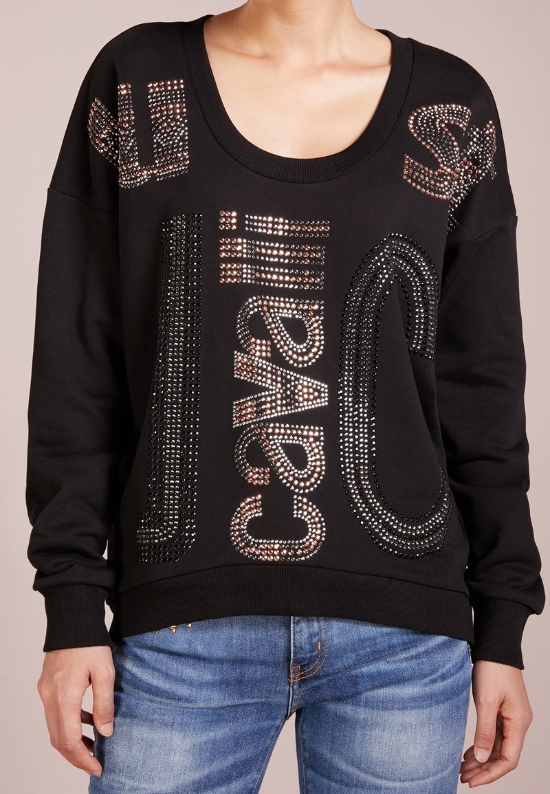 Sudadera negra con un amplio escote circulares y mangas largas, adornada con brillantes rhinestones que forman diseños de texto.