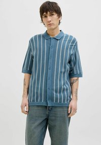 Chemise à manches courtes en turquoise avec des rayures verticales bleu clair, dotée d'un col et d'une coupe décontractée. Tissu texturé.