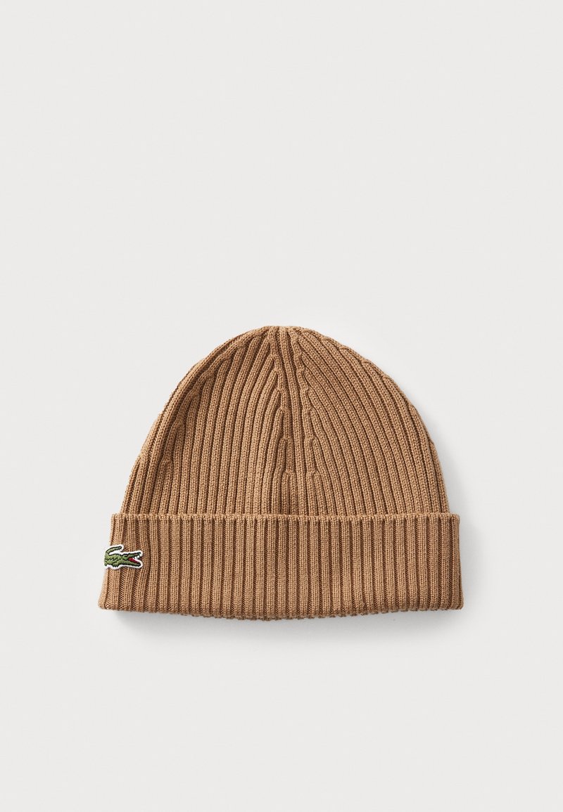Bonnet en maille côtelée marron avec revers plié et petit logo crocodile vert sur le côté, sur un fond clair uni.