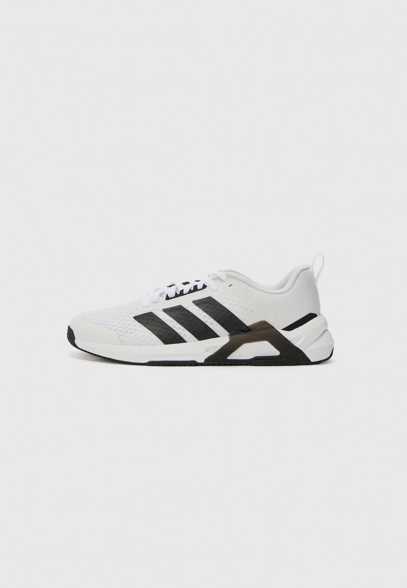 Chaussure de sport blanche avec des accents noirs. Tige en maille, bout arrondi, semelle en caoutchouc noir, et trois rayures noires sur le côté. Conçue pour la polyvalence.