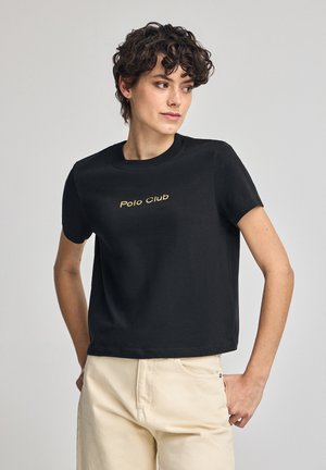 T-shirt noir à manches courtes en coton, avec un col rond et le texte doré "Polo Club" brodé sur le devant.