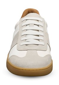 Sneaker mit einem Obermaterial aus beigem Wildleder, weißen Lederakzenten und einer braunen Gummisohle. Runder Zehenbereich und flache weiße Schnürsenkel.