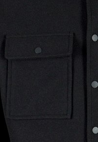 Zwarte, knoopsluiting shirt met een gladde textuur, grote borstzak met een klep en bijpassende zwarte drukknoopjes.