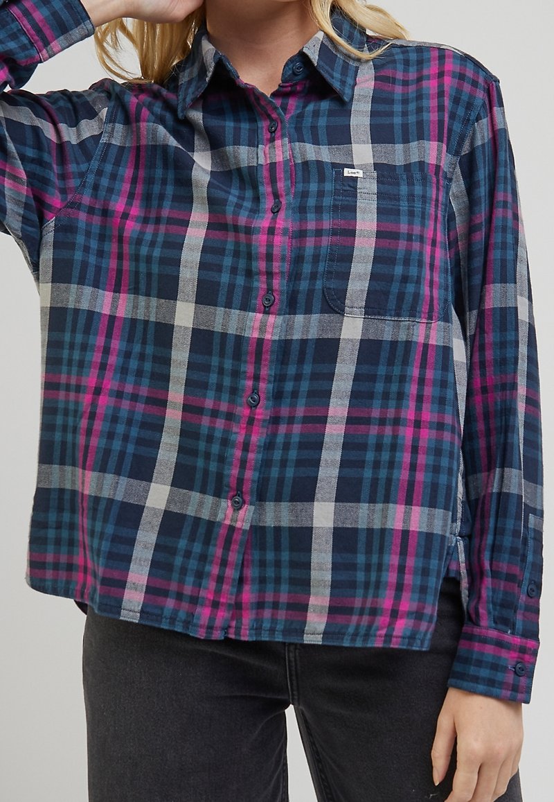 Marinblå och flerfärgad rutigt flanellskjorta med långa ärmar, knäppning framtill och en ficka på bröstet. Har inslag av rosa, grått och teal.