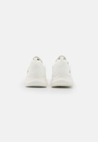 Weiße Sportschuhe mit einem strukturierten Mesh-Obermaterial, gepolsterter Kragen und einer Gummisohle, die ein hellblaues Logo an der Ferse besitzt.