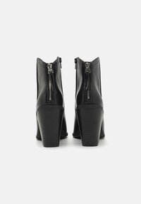 Schwarze Leder-Ankle-Boots mit hohem Blockabsatz, seitlichem Reißverschluss und glatter, strukturierter Oberfläche. Rippendetail am Absatz.
