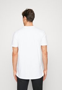 Hvid bomulds t-shirt med korte ærmer, rund halsudskæring og en afslappet pasform. Enkel design uden mønstre eller synlig branding på bagsiden.
