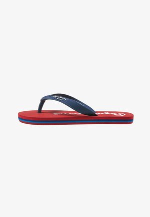 Chancla roja con suela a rayas azul y roja y tiras texturizadas azul marino con texto de marca en blanco.