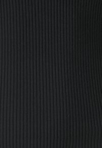 Tela negra acanalada de cerca, con líneas verticales y superficie texturizada. El material parece suave con un ligero estiramiento.