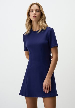Navyblauwe korte jurk, aansluitend bij het lijfje en voorzichtig uitlopend. Glad stof met subtiele stiksels en een ronde halslijn.