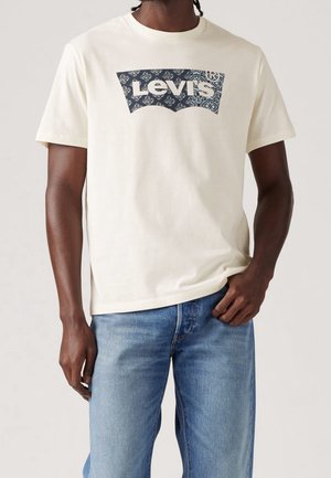 Beige cotton t-shirt featuring a blue patterned Levi's logo on the front. Short sleeves and a crew neckline; relaxed fit.
