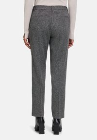 Grau, strukturierte Hose mit einem subtilen Fischgrätenmuster, schlanker Schnitt und Gesäßtaschen; kombiniert mit schwarzen Stiefeletten mit Absatz.