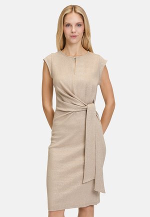 Beige wrap dress made of glittery fabric, featuring cap sleeves, a keyhole neckline, and a tied waist detail. Smooth texture, form-fitting shape.