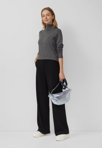 Chandail à col roulé gris, pantalon large noir et baskets blanches. Sac à main en métal argenté avec bandoulière. Design simple et moderne.