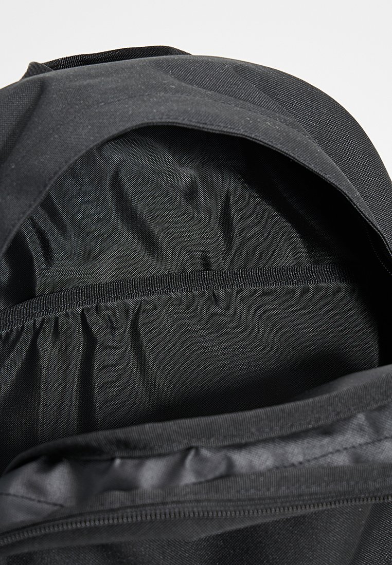 Czarny plecak od wewnątrz wykonany z gładkiego, teksturowanego materiału. Posiada główną przegrodę z zasuwaną kieszenią wzdłuż górnej krawędzi.