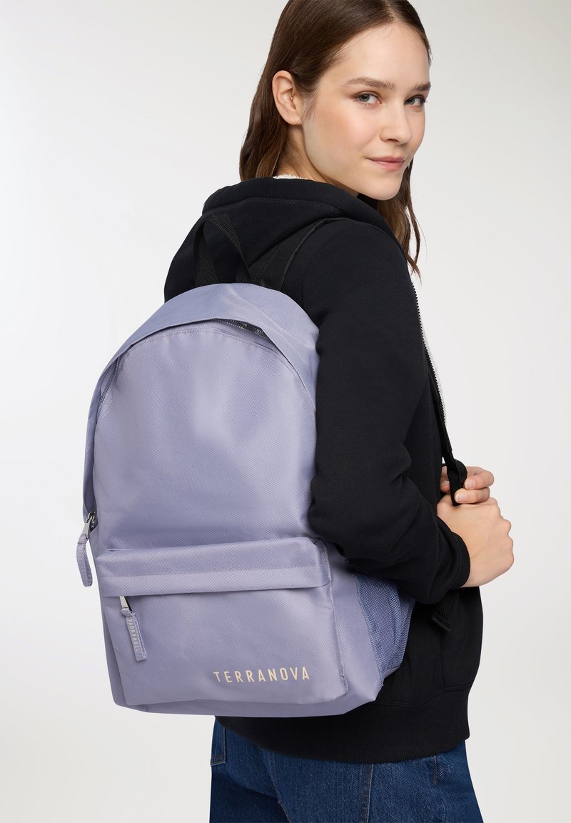 Zaino viola chiaro con finitura testurizzata, tasca frontale, logo dorato "TERRANOVA" e spallacci neri regolabili, indossato sopra un hoodie nero.