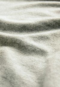 Siva tkanina s glatkom teksturom, koja sadrži suptilne uzorke i nabore, što ukazuje na lagani i fleksibilni materijal.
