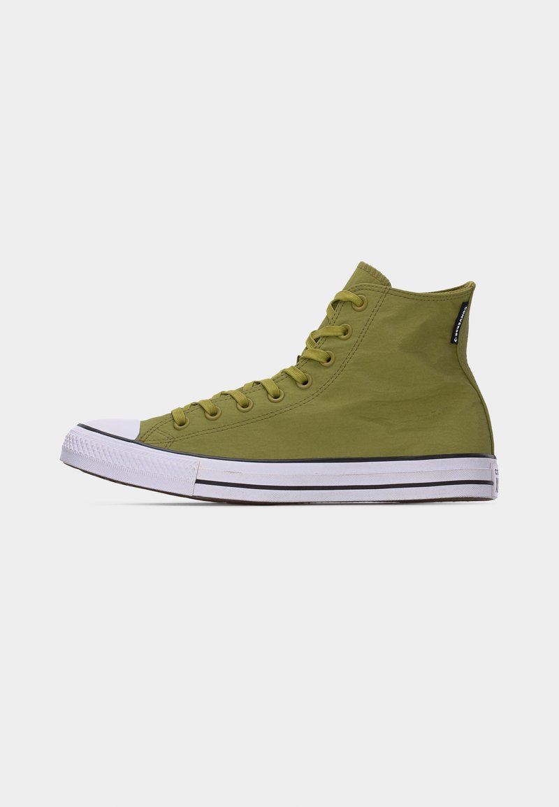 Zapatilla de caña alta de color verde oliva con suela de goma blanca, detalle de raya negra y cordones verdes a juego sobre un fondo blanco liso.