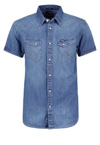 Camicia di jeans corta a maniche corte di colore blu con chiusura a bottoni, colletto a punta e due tasche sul petto caratterizzate da cuciture zigzag e bottoni metallici.
