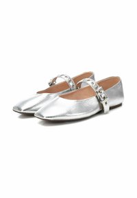 Bailarinas metálicas plateadas con punta afilada, que cuentan con una sola correa ajustable adornada con acentos de hardware en forma de círculos. Suela plana.
