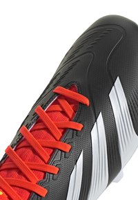 Scarpa da calcio nera con upper testurizzato, caratterizzata da lacci e dettagli rosso brillante. Strisce argento notevoli sui lati e linguetta imbottita.