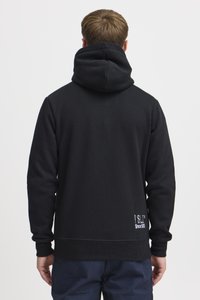 Sudadera negra con gran capucha, puños y dobladillo acanalados. Presenta un estampado de logo en la parte trasera. Textura suave, diseño casual.