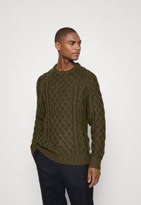 Suéter de punto trenzado en verde oliva con cuello redondo y patrón texturizado, que cuenta con mangas largas y puños y dobladillo acanalados.