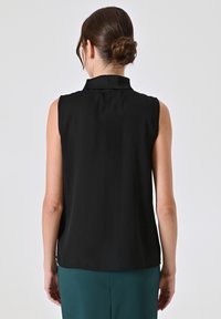 Zwarte afgesloten blouse zonder mouwen met een kraag, van zachte stof en een relaxte pasvorm. Heeft een rechte zoom en geen zichtbare patronen of accenten.