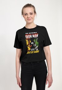 Sort bomulds T-shirt med et grafisk design af Iron Man og Doctor Doom. Teksten inkluderer "Den uimodståelige Iron Man vs. Doctor Doom!"
