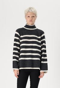 Svītrots turtlenecks džemperis tumši pelēkā un baltā krāsā, izgatavots no ribotās vilnas, ar brīvu piegriezumu un platām piedurknēm.