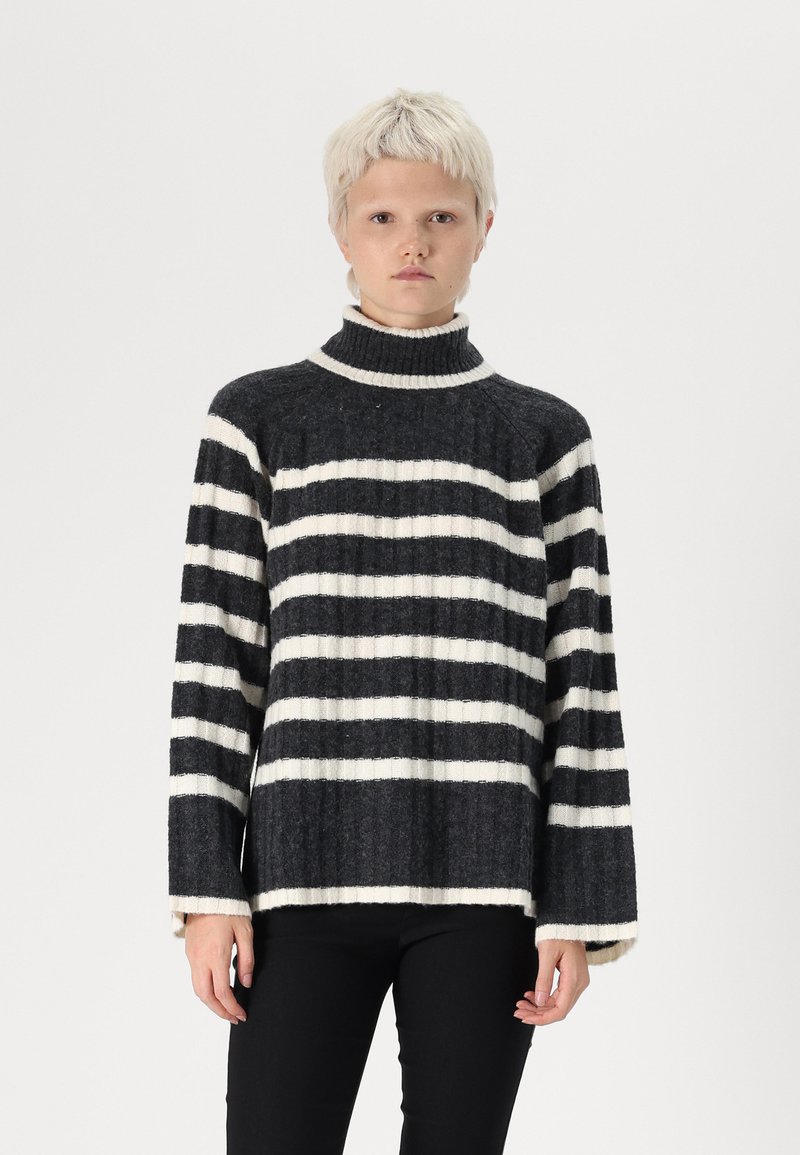 Svītrots turtlenecks džemperis tumši pelēkā un baltā krāsā, izgatavots no ribotās vilnas, ar brīvu piegriezumu un platām piedurknēm.
