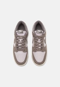 Nike tenisky s kombináciou svetlofialovej kože a hnedej semišovej látky, okrúhla špička, perforované detaily a ploché šnúrky.