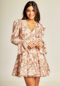 Vestido floral en un suave tono rosa con mangas largas y acampanadas. Presenta un escote en V, tela texturizada y acentos perlados en el dobladillo y los puños.