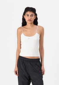 Camisola sem mangas de cor cinza claro com alças finas tipo spaghetti e um pequeno logótipo da Nike no peito, textura suave e um design ajustado.