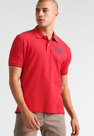 Polo shirt rosso in cotone con colletto, maniche corte e un logo blu ricamato sul petto. Presenta un bordo a contrasto sulle maniche.