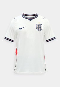 Άσπρη ποδοσφαιρική φανέλα της Αγγλίας με κοντά μανίκια και σκούρα μπλε και κόκκινη επένδυση, με το έμβλημα των Τριών Λιονταριών και ένα χρυσό αστέρι πάνω από αυτό.