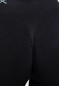 Leggings neri realizzati in tessuto elastico, con un design senza cuciture e una superficie liscia, caratterizzati da una cucitura centrale che mette in risalto la vestibilità.