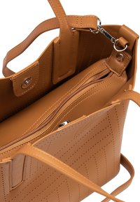 Sac à main en cuir tan avec une poche intérieure zippée, une surface texturée et des détails perforés, équipé de poignées courtes et d'une fermeture à pression.