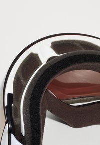 Innholdet i skihjelmen med svart og grå skumdemping, hvit ytre skall, røde detaljer og glatt tekstur; designet for komfort og sikkerhet.