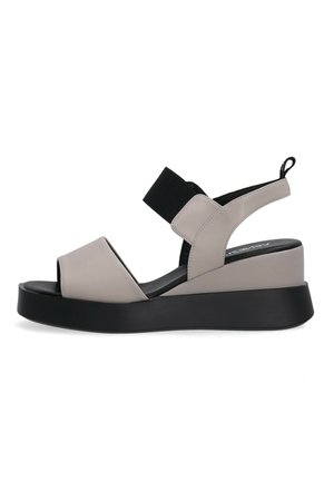 Beige und schwarze Keilsandale mit offenem Zehenbereich, elastischem Riemen über dem Spann, Slingback-Fersenriemen und schwarzer Zuglasche hinten.