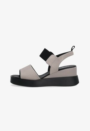 Beige und schwarze Keilsandale mit offenem Zehenbereich, elastischem Riemen über dem Spann, Slingback-Fersenriemen und schwarzer Zuglasche hinten.
