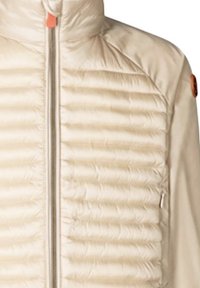 Giacca puffer beige con trapuntatura verticale e colletto alto. Presenta una cerniera frontale, tessuto liscio e un piccolo logo arancione accentato sulla spalla.