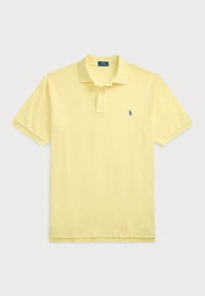 Tricou polo în galben deschis, realizat din bumbac moale. Prezintă un guler cu două butoane și un logo brodat pe partea stângă a pieptului. Mâneci scurte.
