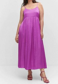 Robe maxi en lavande vibrante, dotée de bretelles spaghetti, d'un corsage ajusté et d'une jupe fluide à volants. Associée à des talons roses à lanières.