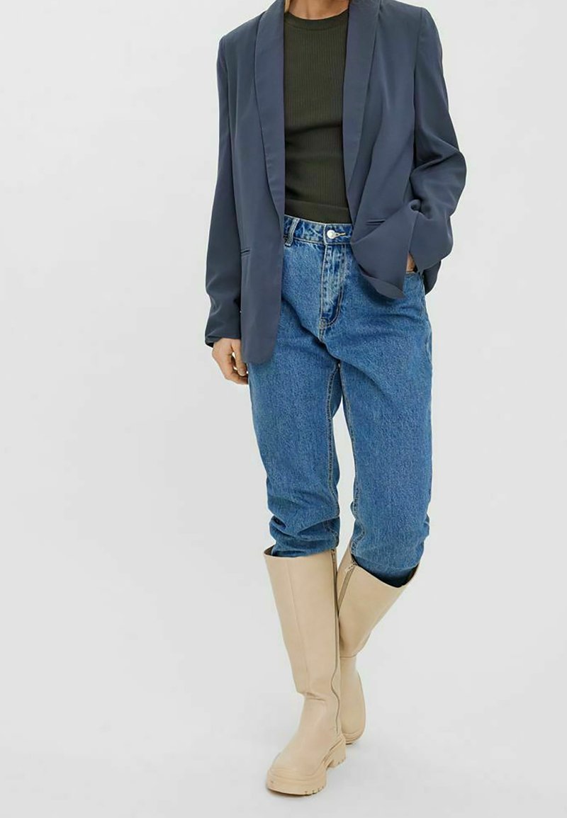 Marinblå kavaj, olivgrön ribbad topp, ljusblå högmidjade jeans och beige knähöga stövlar. Mjuk tygkvalitet, skräddarsydd passform och minimalistisk design.