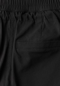 Shorts en tissu noir avec une taille élastique, texture lisse et une poche arrière unique avec un détail de couture horizontal.