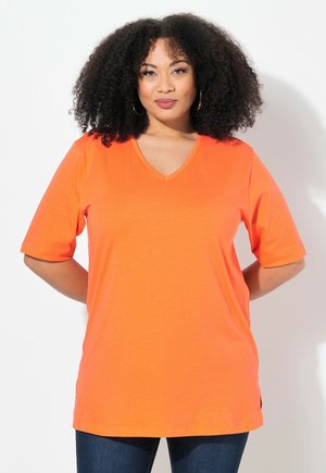 T-shirt a manica corta e scollo a V in cotone arancione brillante, con una vestibilità comoda e spacchi laterali per facilitare i movimenti.